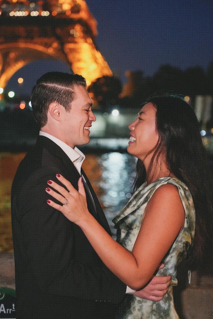 a man and woman standing next to each other in front of the eiffel tower