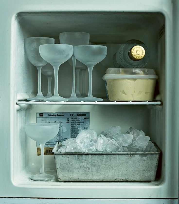 an open refrigerator with ice and wine glasses