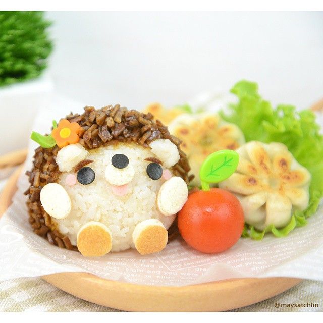 a plate topped with rice covered animals next to veggies and fruit on a table