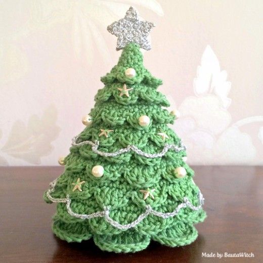 a small crocheted christmas tree on a wooden table with a star ornament