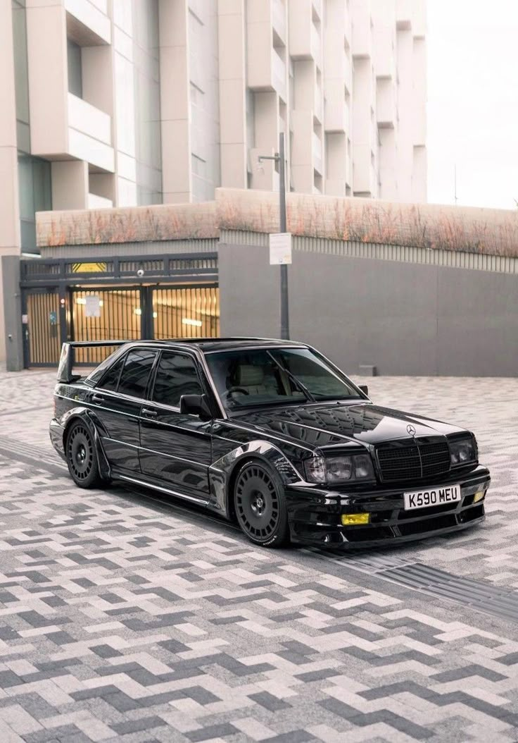 a black car parked in front of a building on a tiled floor next to a parking meter