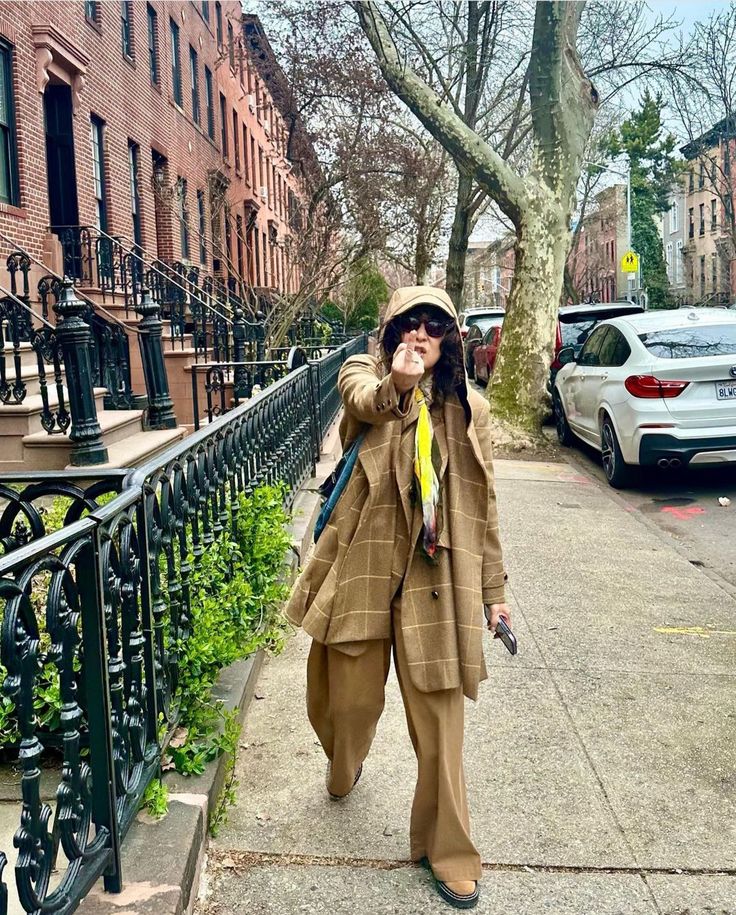 a woman taking a selfie while walking down the sidewalk in front of some buildings