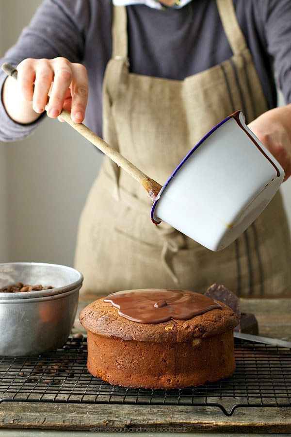 a person pouring chocolate frosting onto a cake