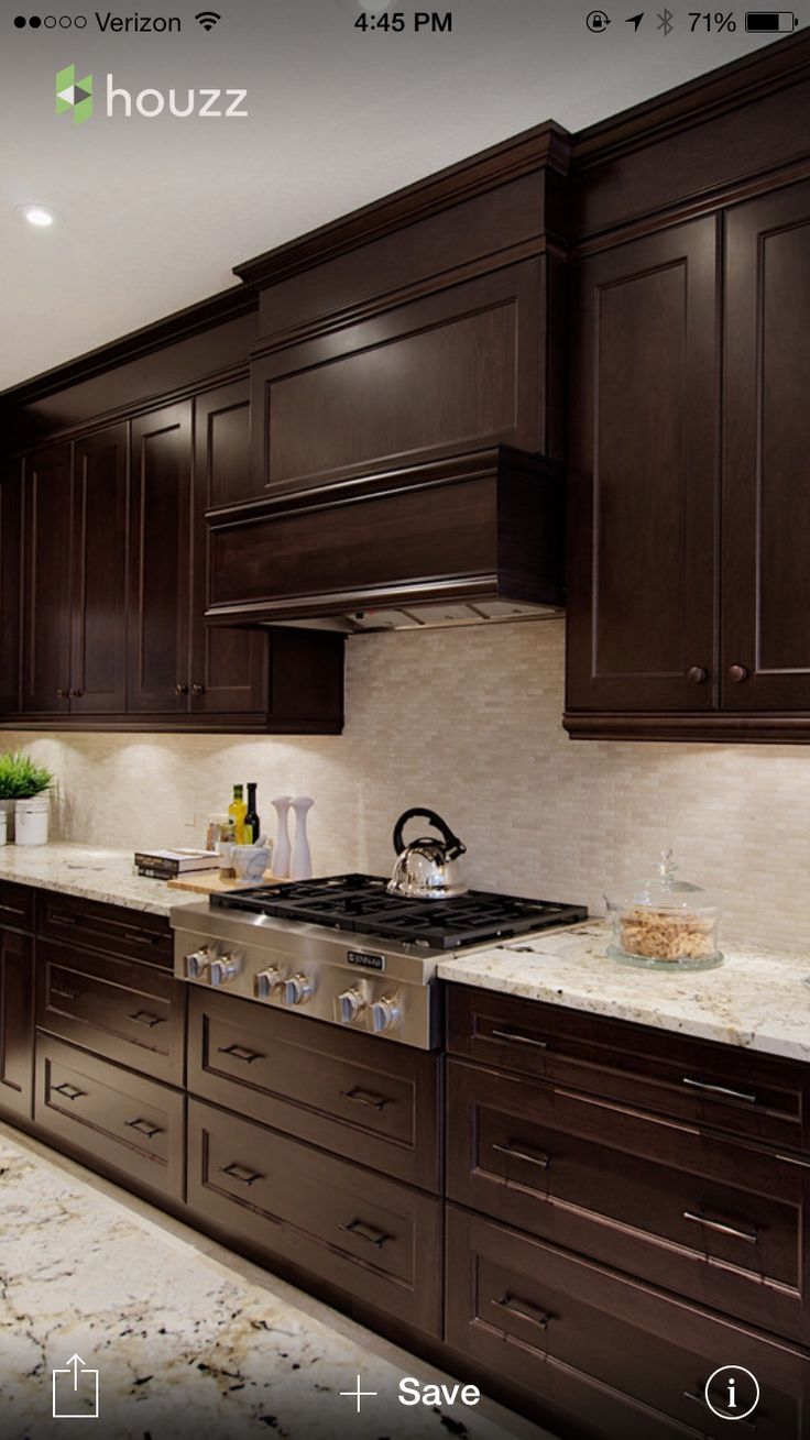 a kitchen with dark wood cabinets and marble counter tops is featured on the phone screen