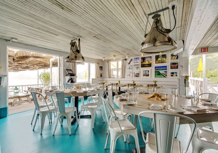 the inside of a restaurant with blue flooring and white tables, chairs and lamps