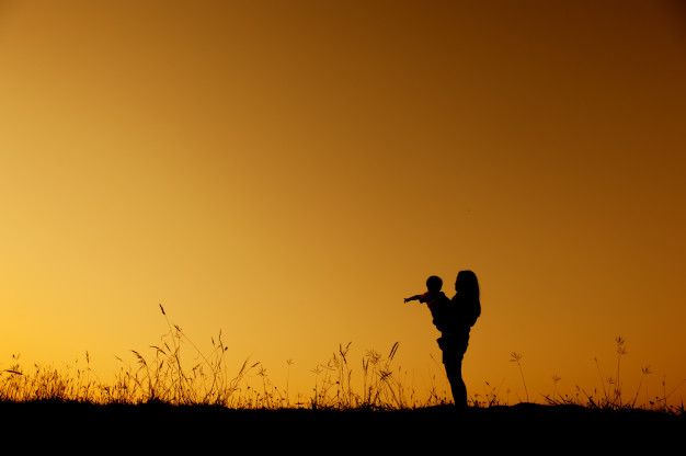 the silhouette of a person pointing at something in the distance with an orange sky behind them