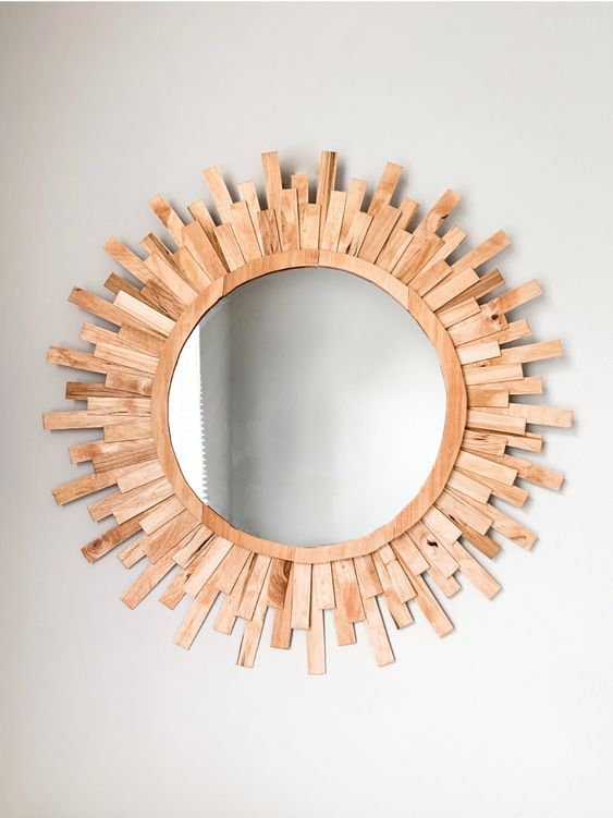 a mirror made out of wood sticks on the wall above it is a sunburst shaped mirror