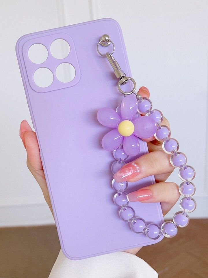 a woman holding a purple phone case with a flower on the front and chain attached to it