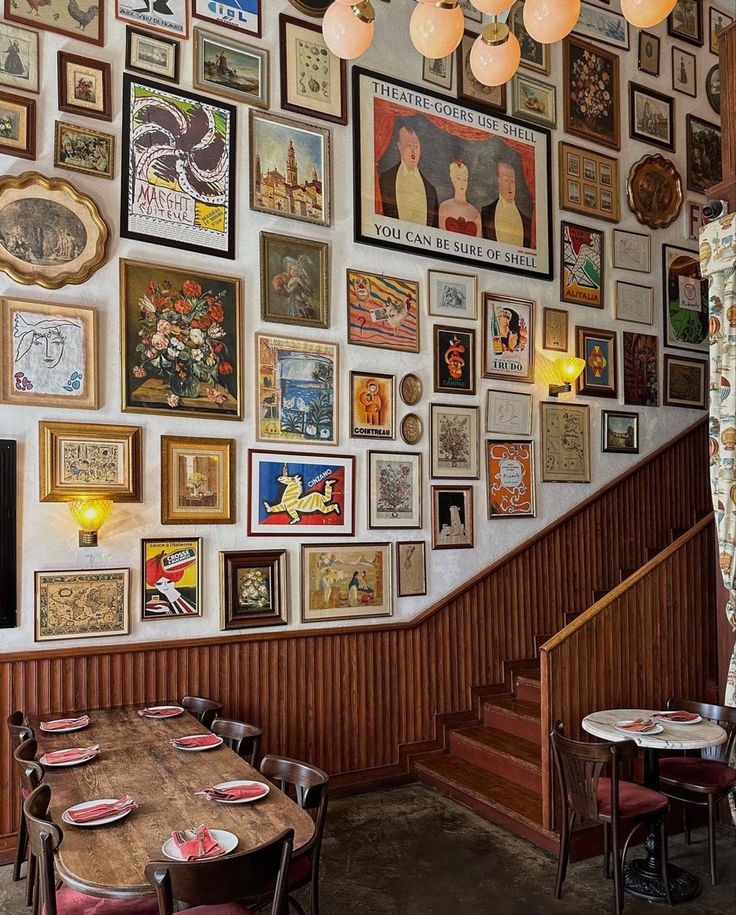 a dining room filled with lots of framed pictures on the wall and wooden tables in front of them