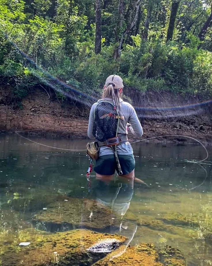 a person standing in the water with a fishing rod