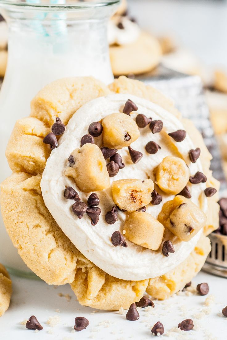 a cookie with bananas and chocolate chips on it next to a glass of milk,