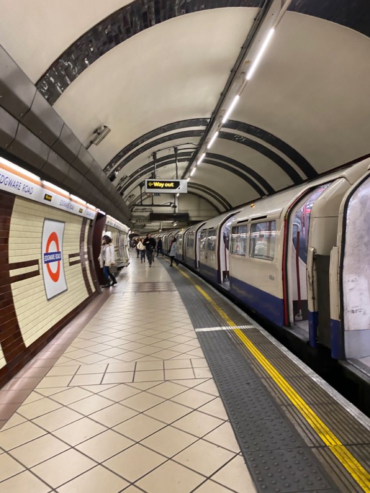 a subway train pulling into the station with people walking on the platform next to it