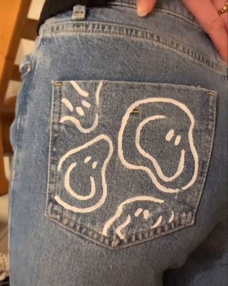 someone is holding their back pocket open to show the inside of their jeans with drawings on them