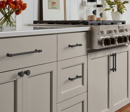 a kitchen with gray cabinets and white counter tops, flowers in vases on the stove