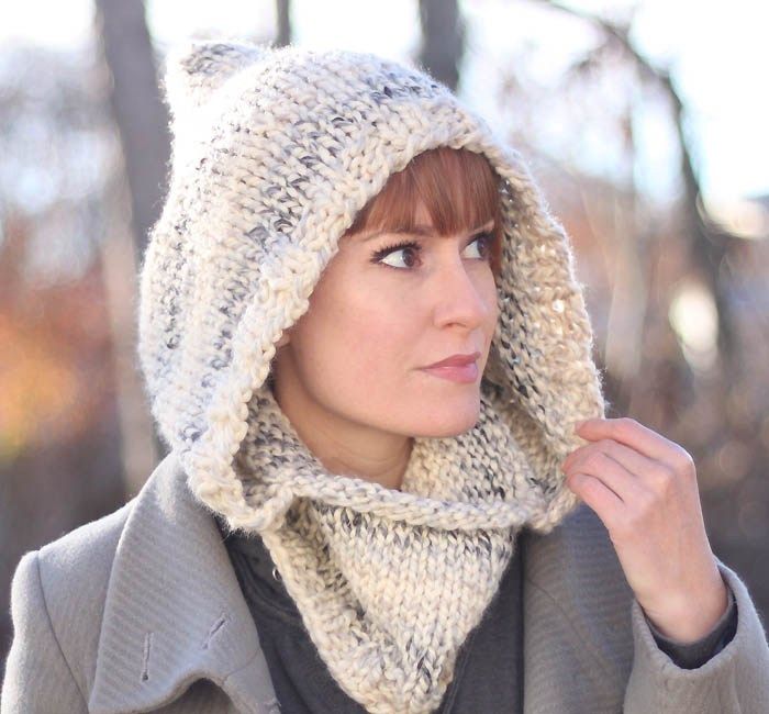 a woman wearing a knitted hat and scarf with a cat hood on her head