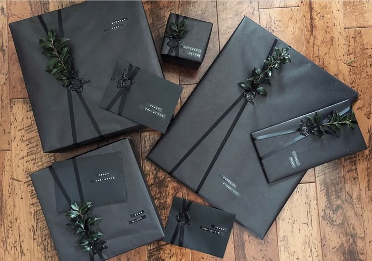 four black wrapped presents with ribbons and bows on them sitting on a wooden floor next to each other