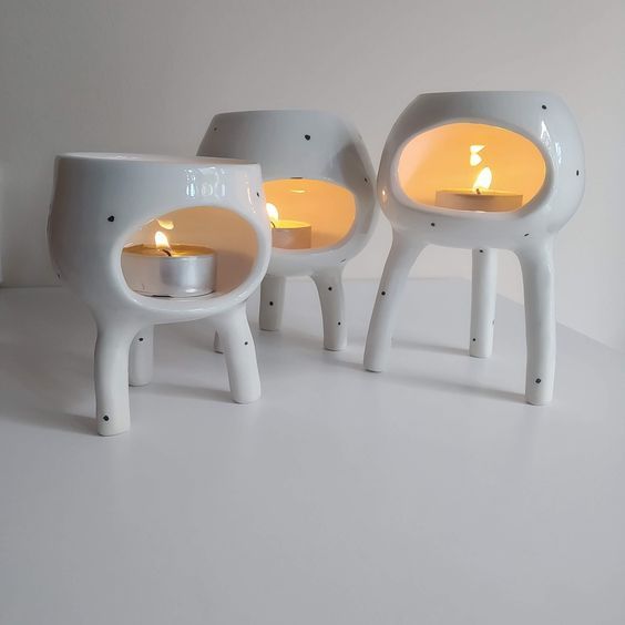 three white objects with candles in them on a table