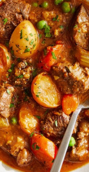 a white plate topped with meat and potatoes covered in gravy next to a spoon