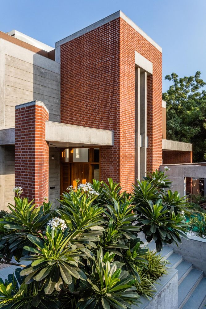 a brick building with plants in front of it and stairs leading up to the entrance