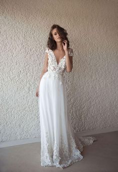 a woman standing in front of a white wall wearing a dress with lace on it