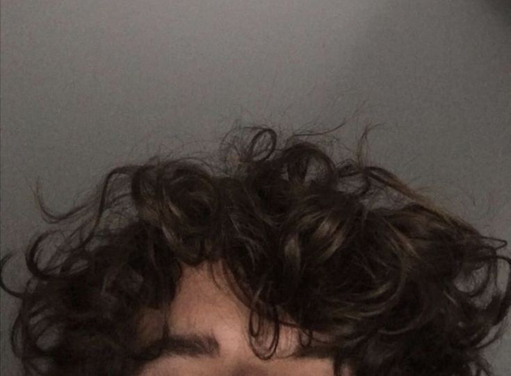 a close up of a person with curly hair and an eye shadow on the wall