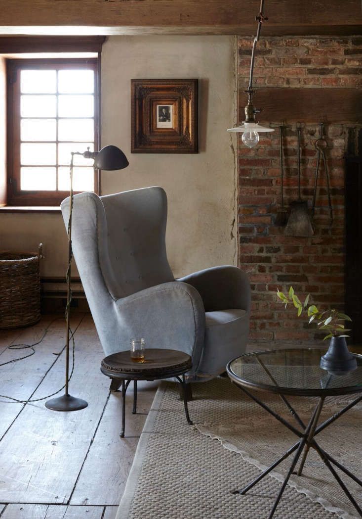 a living room filled with furniture and a fire place next to a brick wall in front of a window