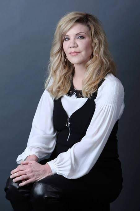 a woman sitting on top of a chair with her arms crossed and looking at the camera