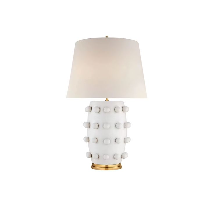 a white table lamp with a gold base and a light shade on the top of it