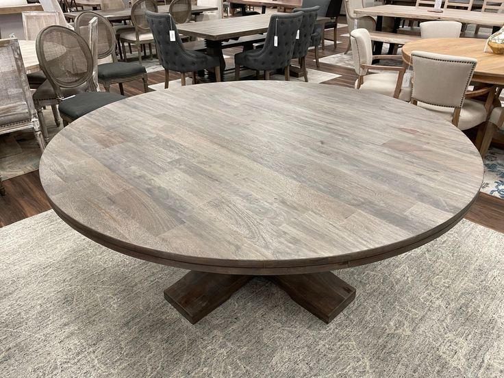 a round wooden table surrounded by chairs and tables in a room with carpeted flooring