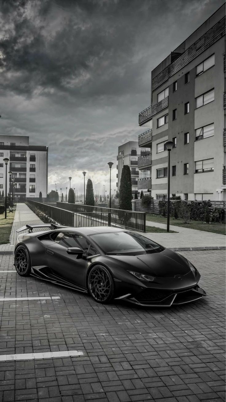 a black sports car parked on the side of a road in front of tall buildings