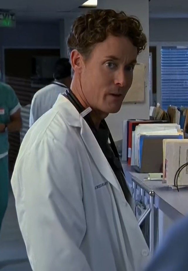 a woman in white lab coat standing next to a counter