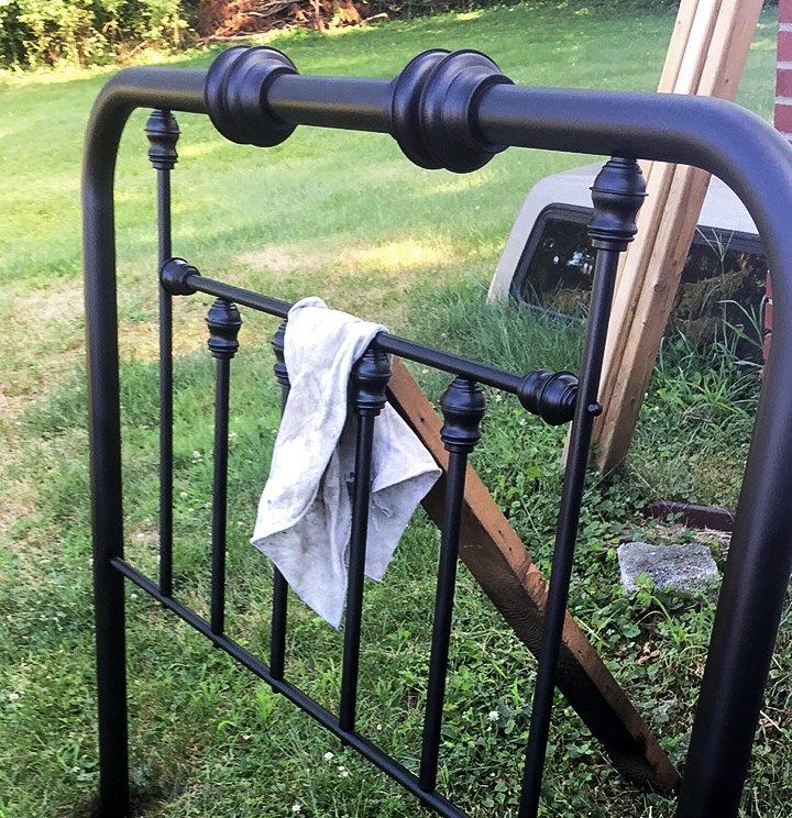 a towel is hanging on the rail of a metal bed frame in front of a house