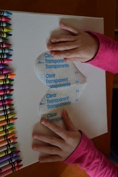 a person holding up a piece of paper with colored crayons in front of it