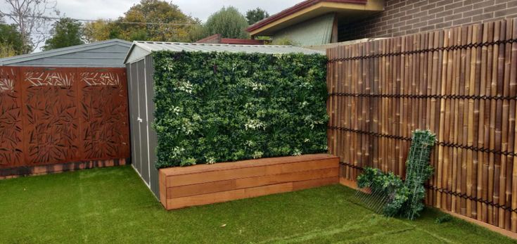 a small garden area with grass and wooden fence