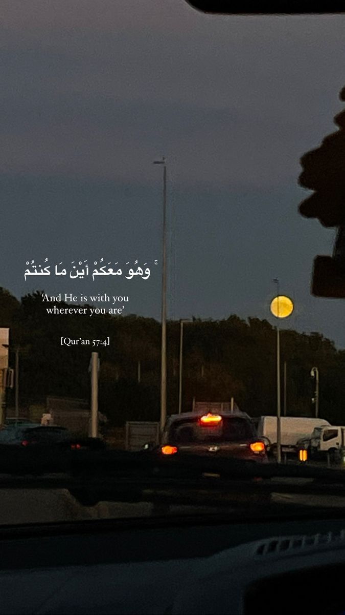 cars driving down the road at dusk with an arabic quote on it's side