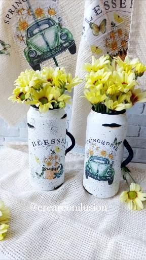 two vases filled with yellow flowers sitting on top of a white cloth covered table