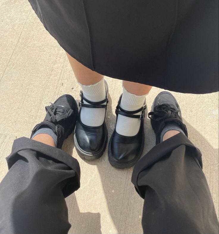 two people wearing black and white shoes standing next to each other with their legs crossed