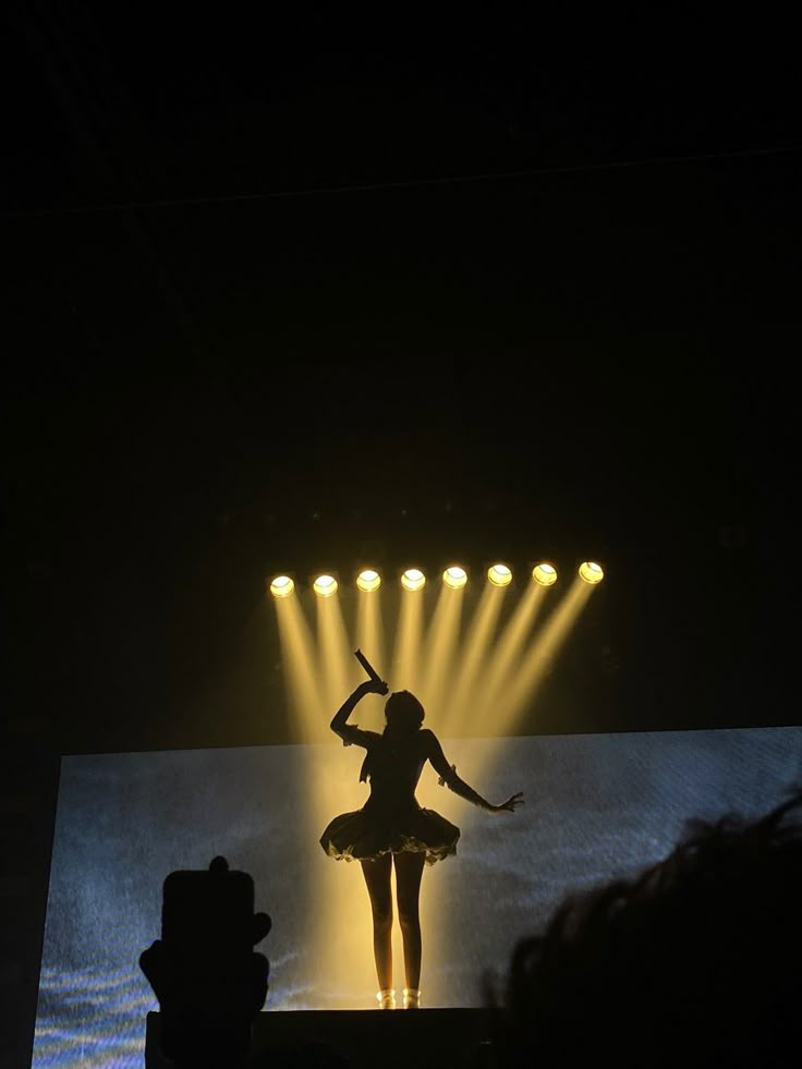 a woman is performing on stage with lights behind her