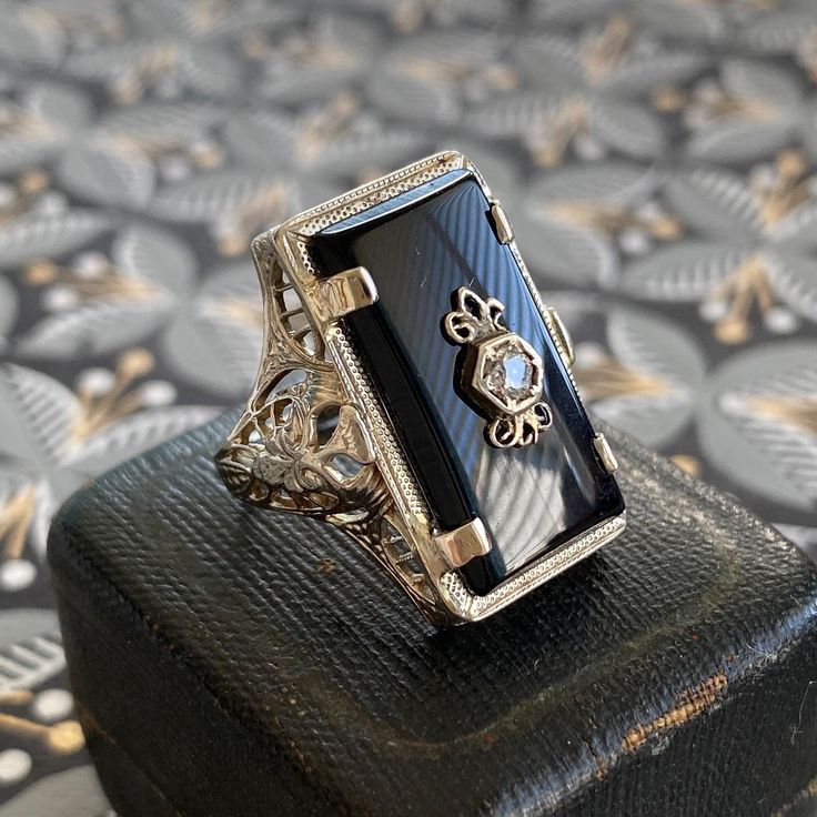 Details: Beautiful vintage onyx set in 14K white gold filigree. The filigree has a lovely art nouveau feel. The onyx is a very rich, deep black, and a rose cut Diamond is set in the center of the onyx stone. Hallmarks on the interior band read P&KCC and 14K. This is a stunning ring--you will not be disappointed! Please ask all necessary questions prior to placing an order. Measurements: The size is 6 US and can be sized for a fee. The stone measures 20mm x 10mm. Ring weighs 4.5 grams. Condit Black Filigree Ring For Formal Occasions, Elegant Engraved Onyx Jewelry, Art Deco Filigree Jewelry For Evening, Elegant Black Hallmarked Jewelry, Formal Black Filigree Ring, Antique Black Jewelry With Polished Finish, Black Filigree Ring With Intricate Design, Art Deco Jewelry With Intricate Design For Evening, Antique Black Wedding Jewelry