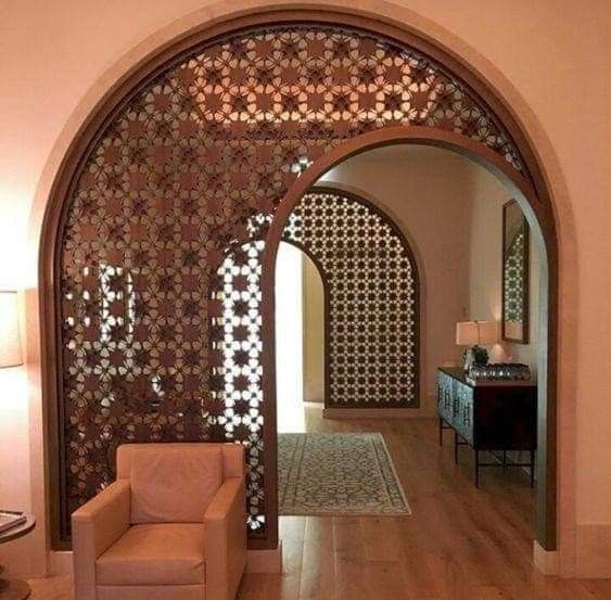 an archway in a living room with a chair and lamp