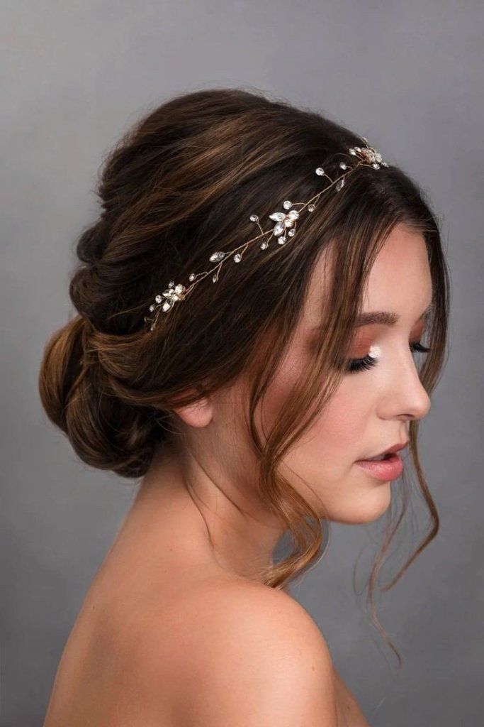 a woman wearing a gold headpiece with flowers on it's side and her hair in a low bun