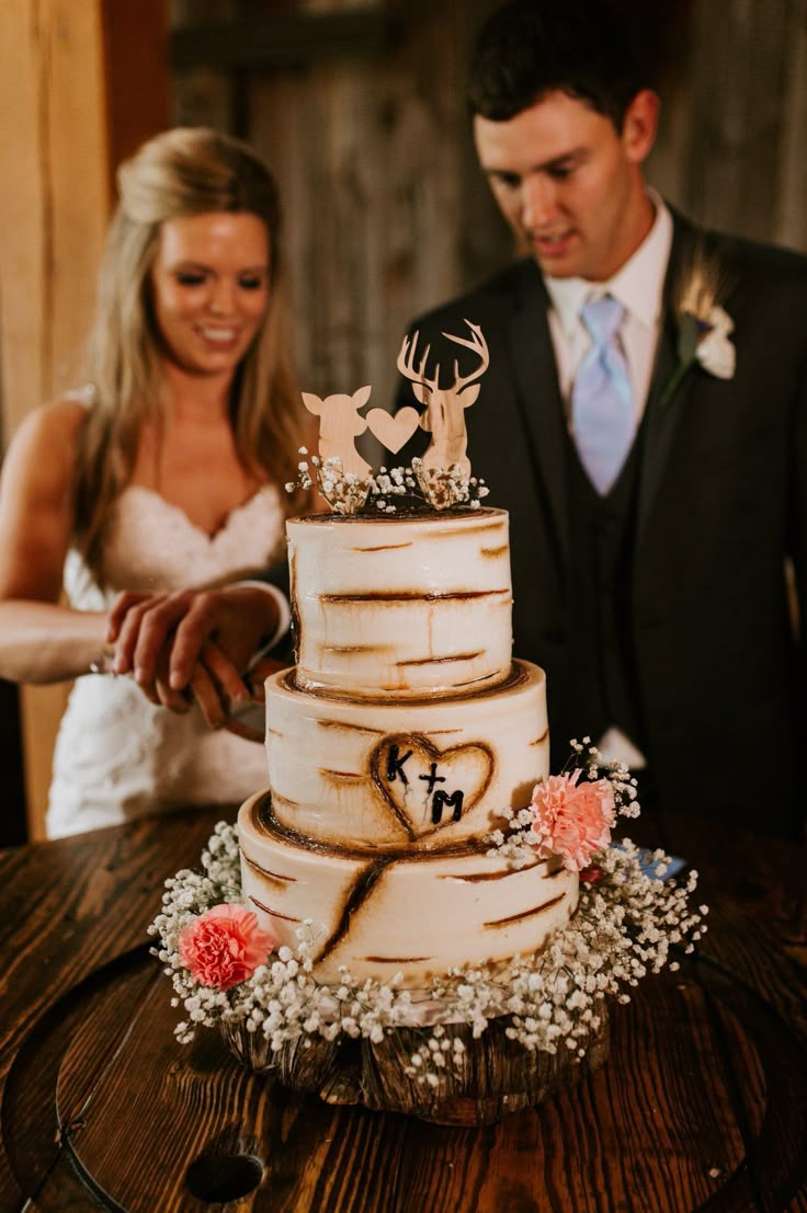 a bride and groom are cutting their wedding cake with deer antlers on the top