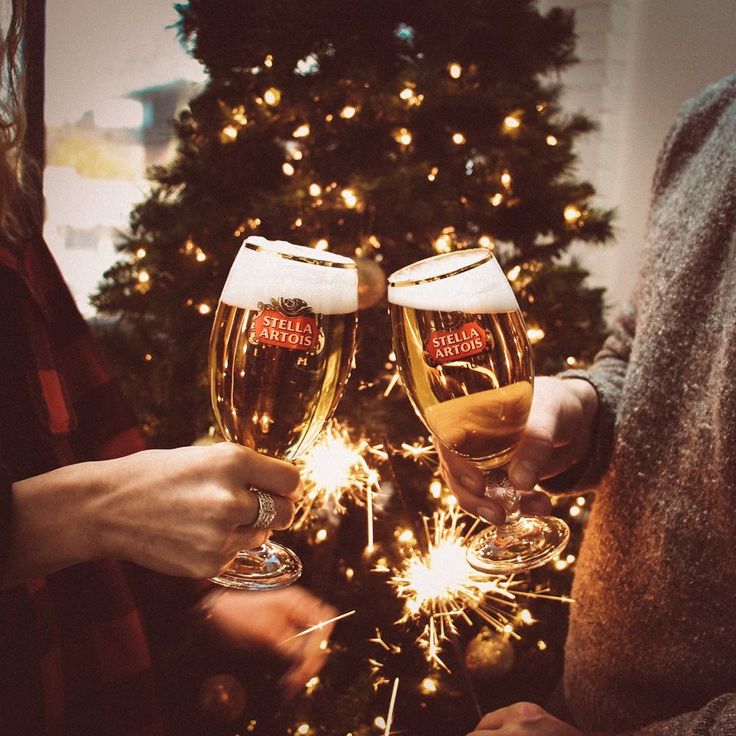 two people toasting with sparklers in front of a christmas tree