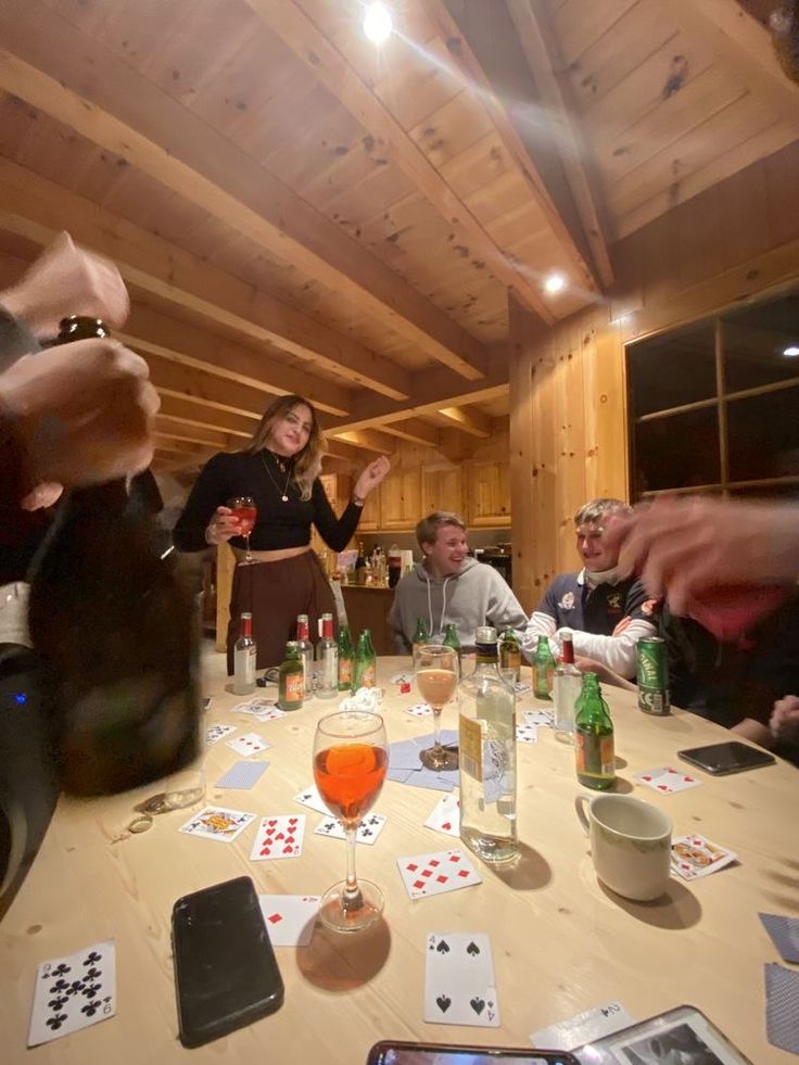 a group of people sitting around a table with cards and wine glasses on top of it