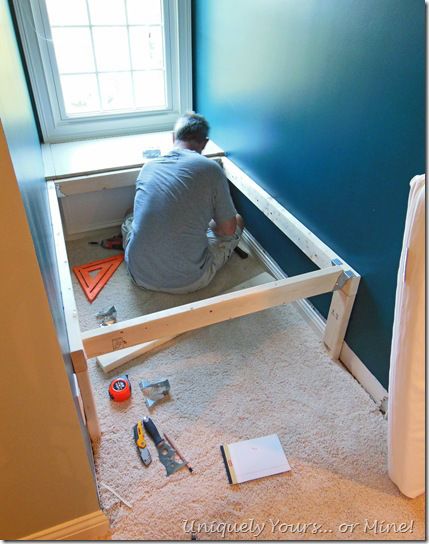 a man sitting on the floor in front of a window with construction tools around him