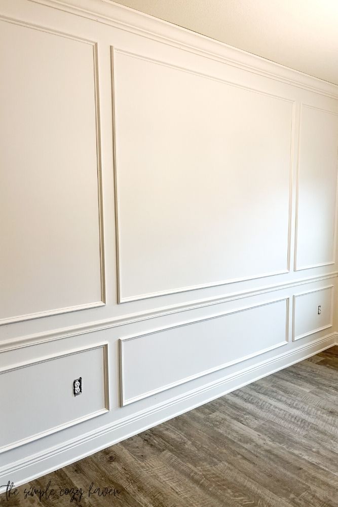 an empty room with white paneling and wood floors