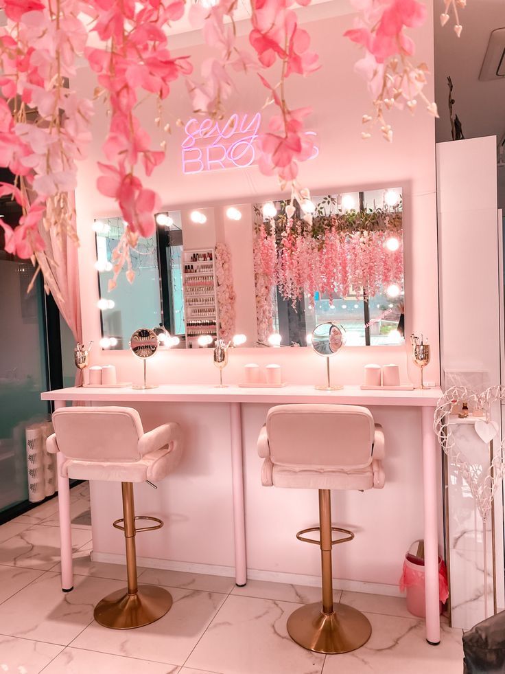 a room with two stools and a mirror on the wall that has pink flowers hanging from it