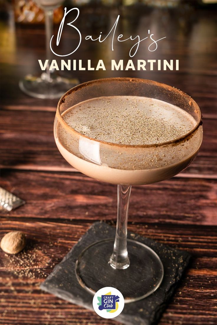 a close up of a drink in a glass on a wooden table with the words bailey's vanilla martini