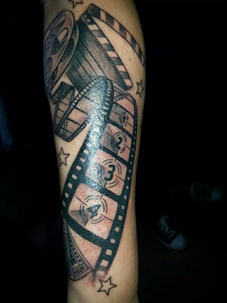 a man's arm with a movie reel tattoo on it and stars around the film strip