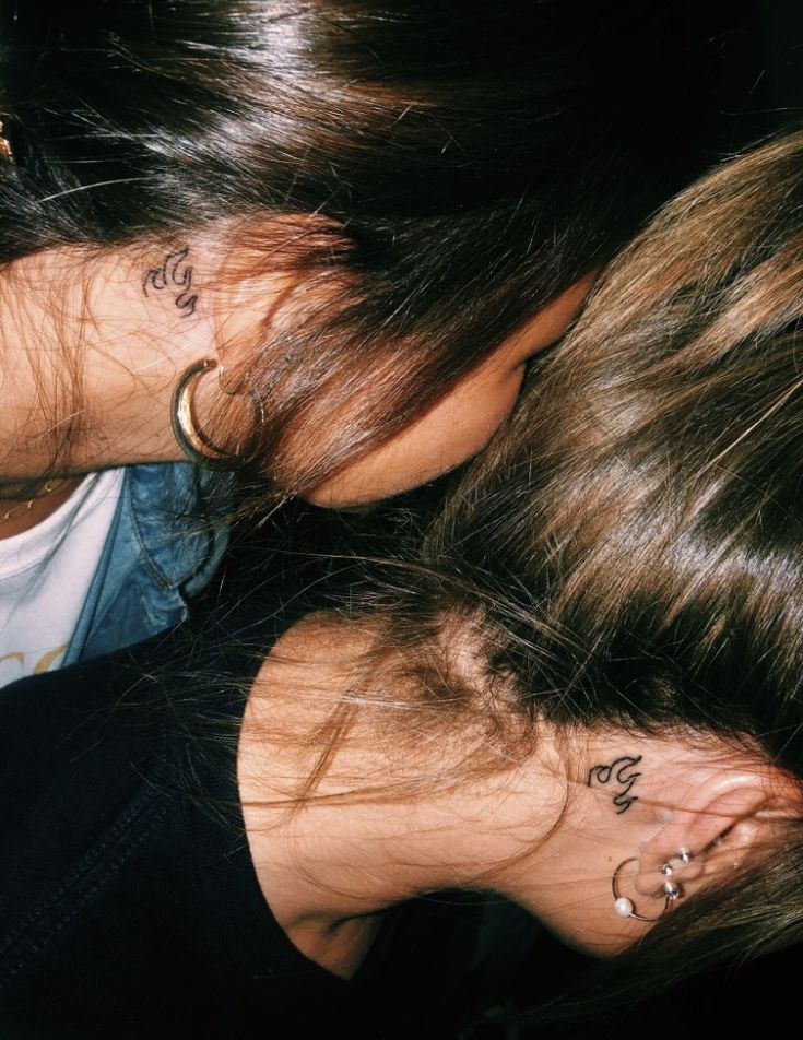 two women with tattoos on their neck and behind them are one woman's head